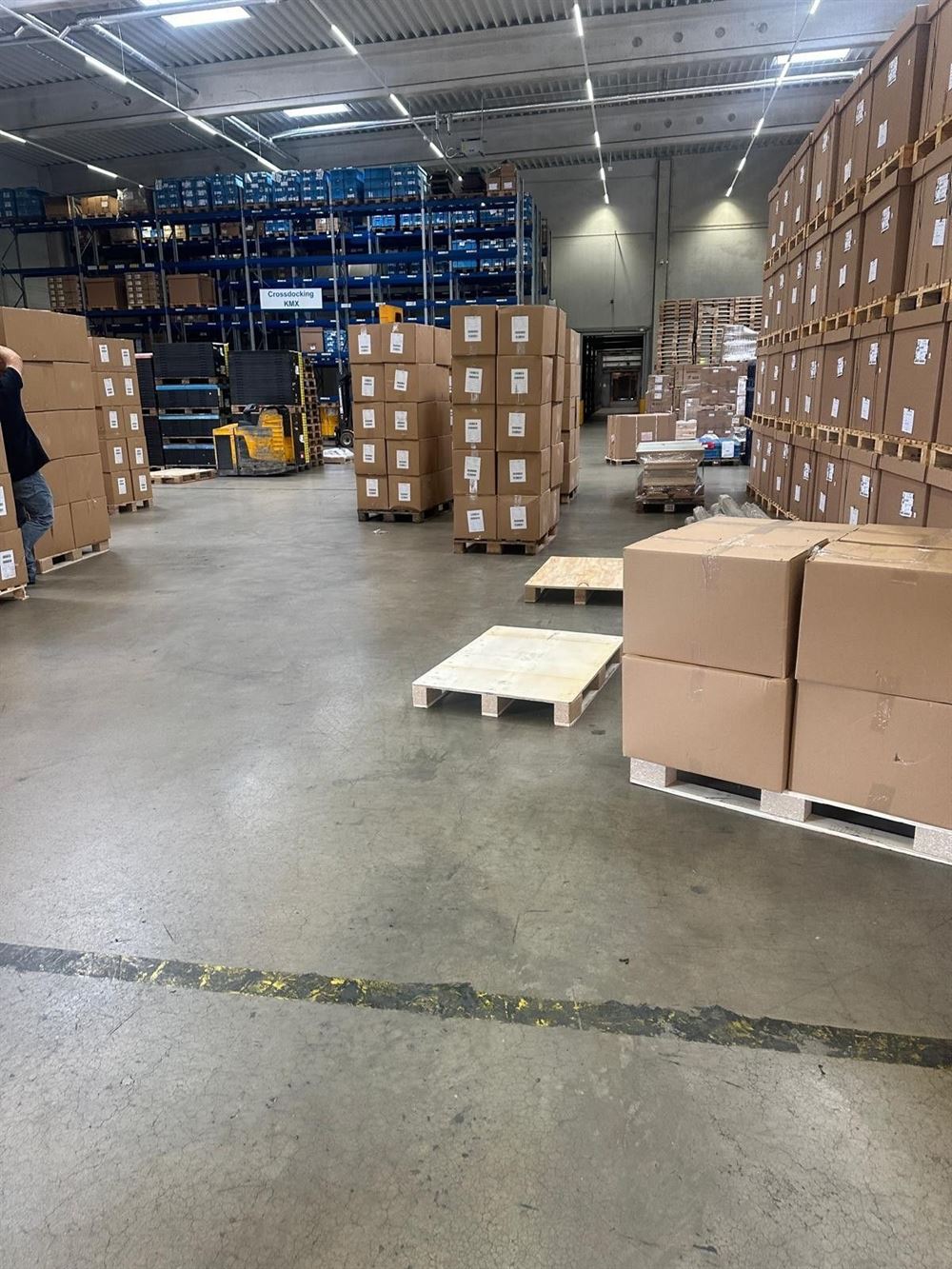 A wide cross-dock floor with stacked pallets of boxes staged for loading.