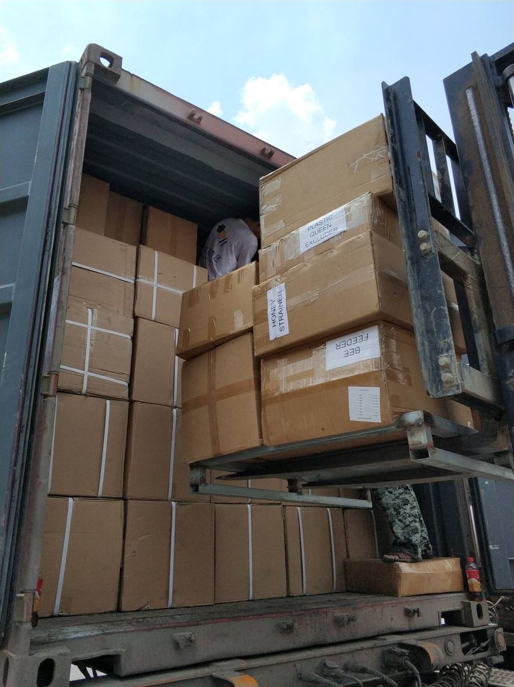 A forklift lifts boxes into a shipping container being packed full.